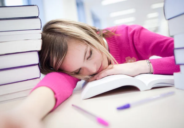 In the library - very tired / exhausted, pretty, female student wi — стоковое фото