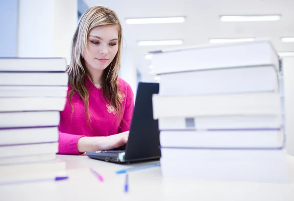 I biblioteket - vacker, kvinnlig student med laptop och böcker wo — Stockfoto