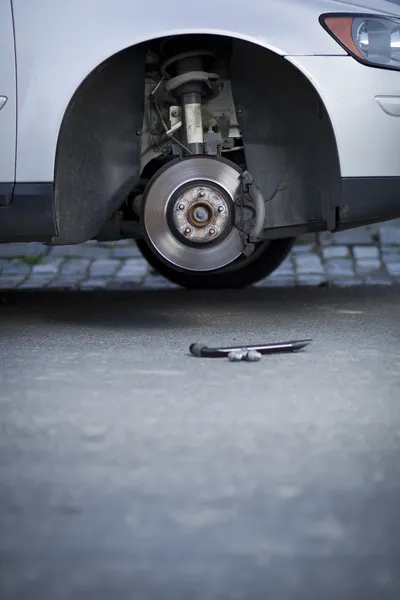 Mecánico cambiando una rueda de un coche moderno — Foto de Stock