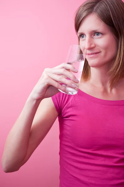 Mujer bonita y joven bebiendo agua dulce de un vaso (tonelada de color — Foto de Stock