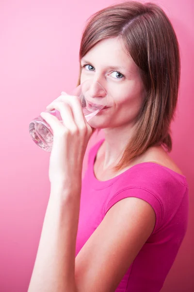 Mujer bonita y joven bebiendo agua dulce de un vaso (tonelada de color — Foto de Stock
