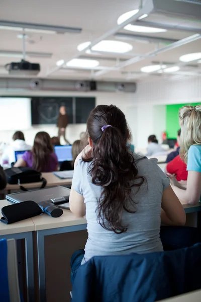 Junge hübsche College-Studentin sitzt in einem Klassenzimmer voll — Stockfoto