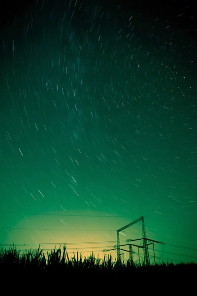 Paesaggio notturno stellato con pali ad alta tensione — Foto Stock