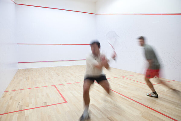 Squash players in action on a squash court (motion blurred image