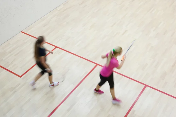 Två kvinnliga squash spelare i snabb action på en squashbana (moti — Stockfoto
