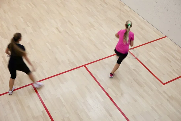 Två kvinnliga squash spelare i snabb action på en squashbana (moti — Stockfoto