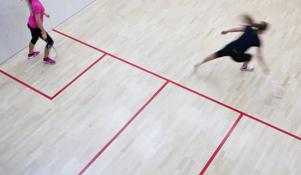 Two female squash players in fast action on a squash court (moti — Stock Photo, Image