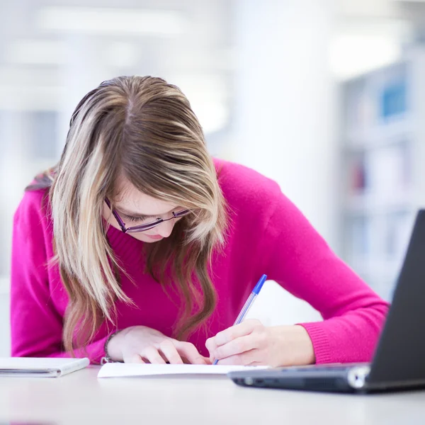 In the library - pretty, female student with laptop and books wo Royalty Free Stock Images