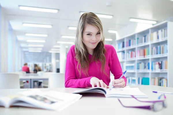 In the library - pretty, female student with laptop and books wo Stock Image