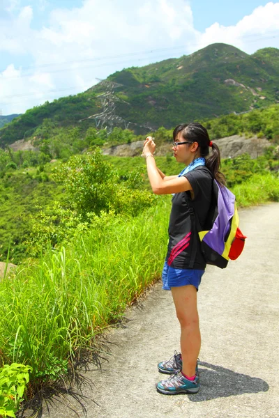 Young woman with backpack hiking and taking a photo — Stock Photo, Image