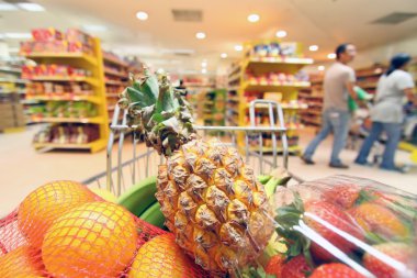 Moving shopping cart in supermarket. clipart