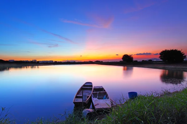 Закат вдоль пруда с двумя лодками и два волшебных цвета на ск — стоковое фото