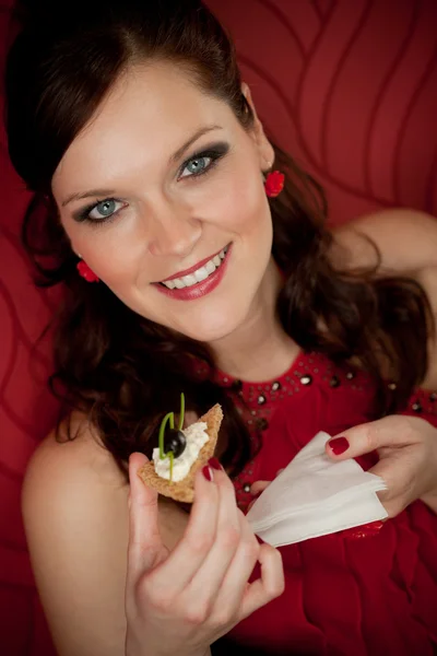Женщина с коктейльной вечеринки ест закуску вечернее платье — стоковое фото