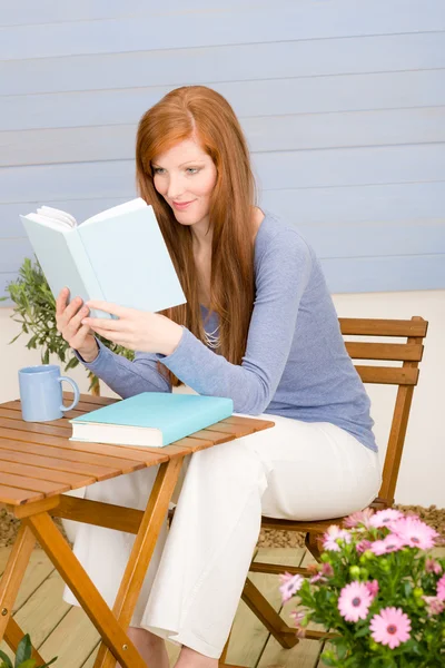 Рыжая женщина с летней террасы читает книги — стоковое фото