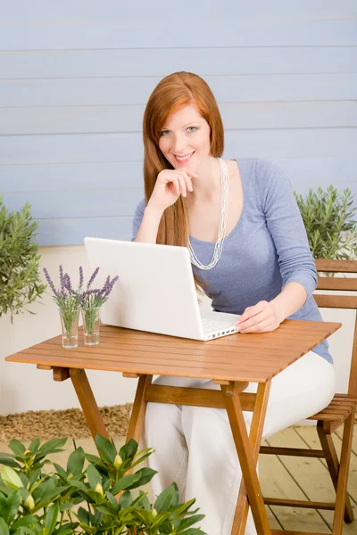 Рыжая женщина на летней террасе с ноутбуком — стоковое фото