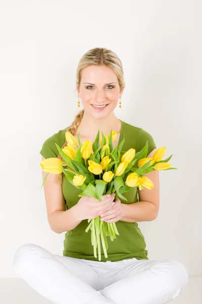 Mulher feliz segurar um monte de tulipas sentado — Fotografia de Stock