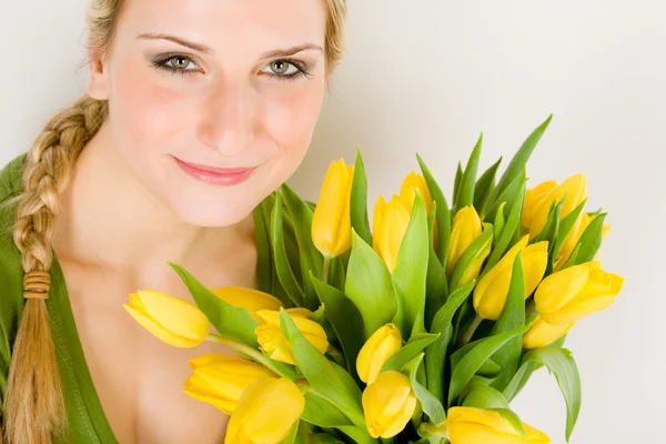 若い女性は、黄色のチューリップの花を保持します。 — ストック写真