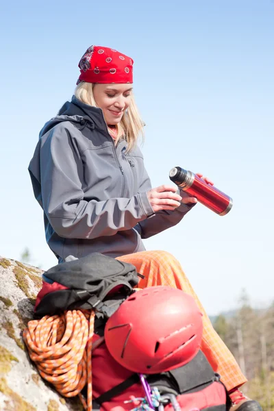 Active woman rock climbing with thermosbottle — Stock Photo, Image