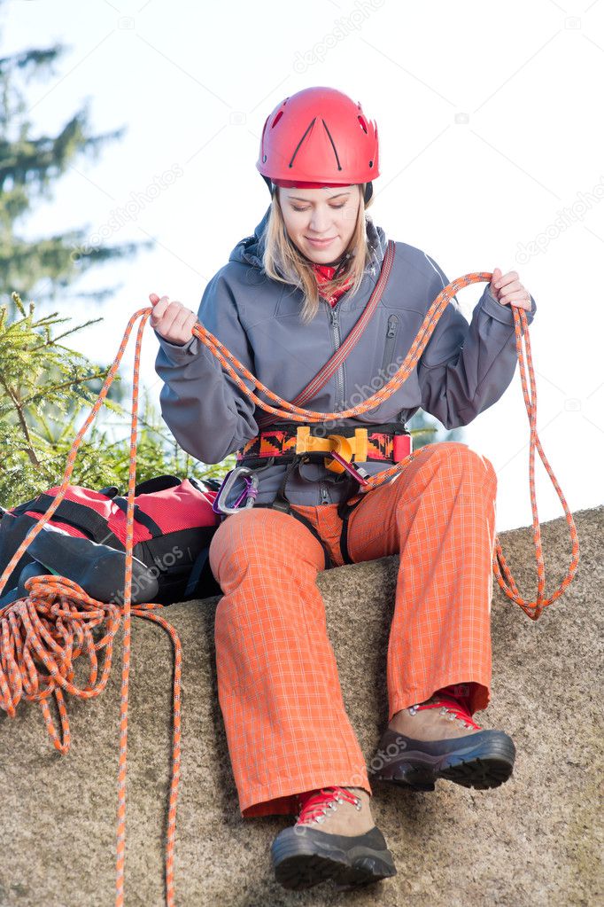 Active woman rock climbing holding rope