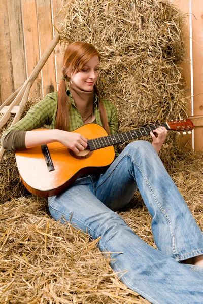 Mladá země žena hrál na kytaru ve stodole — Stock fotografie