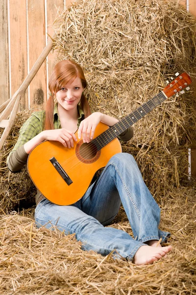 Mladá země žena sedí na seno s kytarou — Stock fotografie