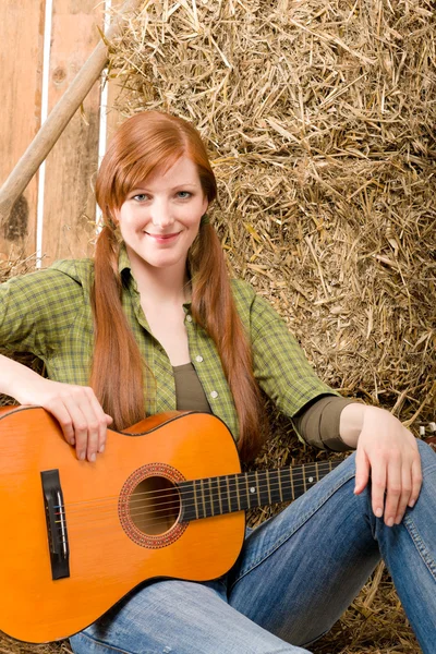 Young country woman sitting on hay with guitar — Stock Photo, Image