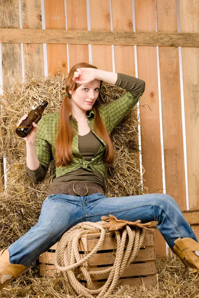 在谷仓里挑衅的年轻女牛仔喝啤酒 — 图库照片
