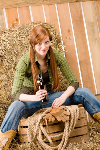 Prowokacyjny cowgirl młody napój piwo w stodole — Zdjęcie stockowe