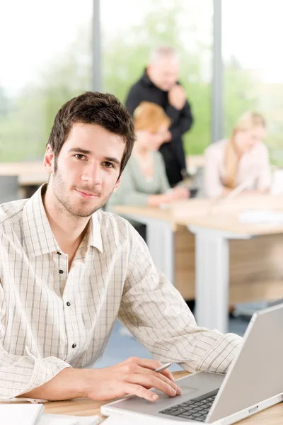 Portrait of young businessman with team in back — Stockfoto