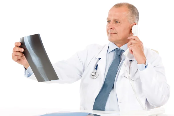 Зрілий старший лікар чоловік дивиться на рентгенівський знімок — стокове фото