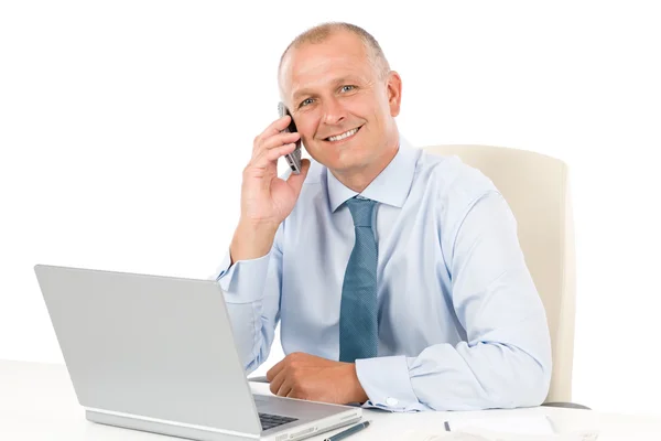 Lächelnder Geschäftsmann sitzt im Büro hinter Schreibtisch — Stockfoto