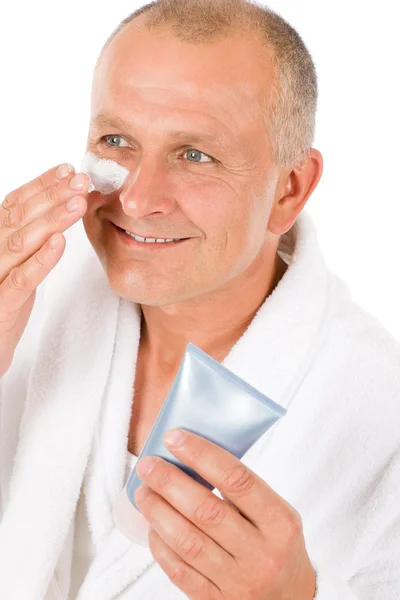 Male cosmetics - senior man apply facial cream — Stock Photo, Image