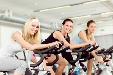 Fitness young woman on gym bike spinning clipart