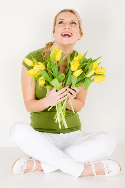 Счастливая женщина держит кучу тюльпанов сидя — стоковое фото