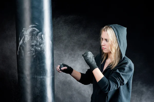 Mulher de boxe loira em saco de perfuração preto — Fotografia de Stock