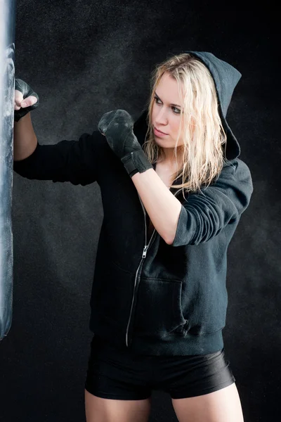 Blond boxing woman in black punching bag — Stock Photo, Image