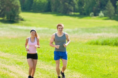 Sportif genç bir çift jogging Meadows güneşli yaz