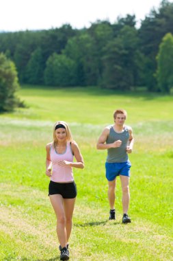 Sportif genç bir çift jogging Meadows güneşli yaz