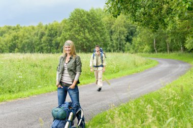 Hiking young couple backpack asphalt road countryside clipart
