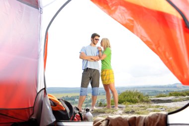 Camping young couple outside tent panoramic view clipart