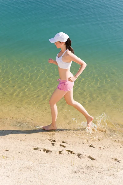 Summer sport fit woman jogging along seashore — Stock Photo, Image
