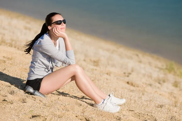 Καλοκαιρινό άθλημα ταιριάζει γυναίκα που κάθεται στην παραλία — Φωτογραφία Αρχείου
