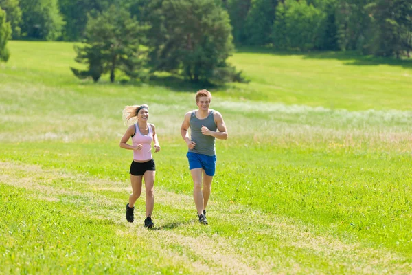 Sportig unga par jogging ängar solig sommar — Stockfoto