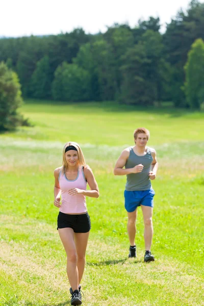 Sportig unga par jogging ängar solig sommar — Stockfoto
