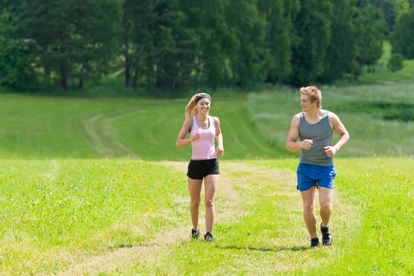 Sportive young couple jogging meadows sunny summer — Stock Photo, Image