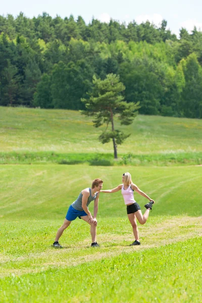Esportivo casal jogging alongamento no campo — Fotografia de Stock