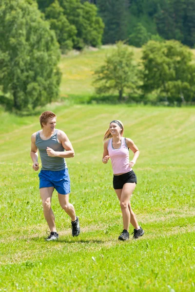 陽気な若いカップル ジョギング草原の日当たりの良い夏 — ストック写真