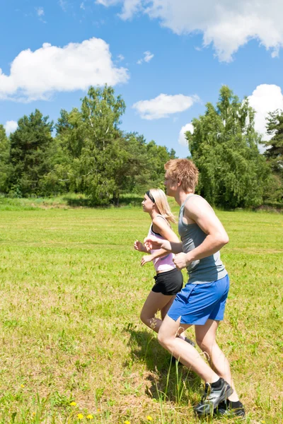 Deportiva joven pareja trotando prados soleado verano — Foto de Stock