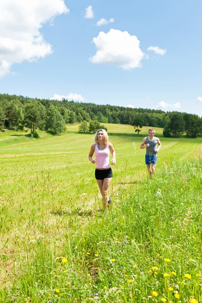 Deportiva joven pareja trotando prados soleado verano — Foto de Stock