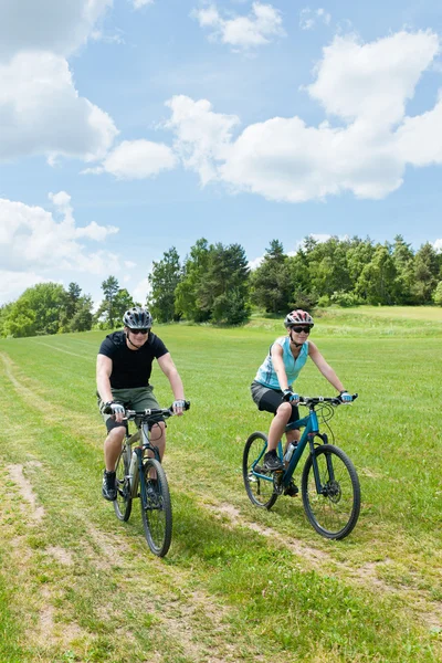 Sport couple riding mountain bicycles in coutryside — Stock Photo, Image